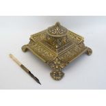 A Victorian cast brass inkwell / Standish of squared form with relief decoration having hinged