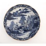 An oriental style blue and white dish. Depicting figures in an oriental landscape with pagodas and