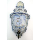 A c1901 Delft style ceramic wall hanging water cistern with lid. Decorated with an image of a cherub