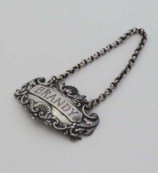 A Victorian silver brandy label with acanthus scroll and shell decoration hallmarked London 1839