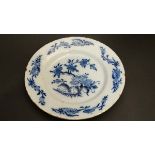 An 18thC Delft plate painted in blue with Chinoiserie floral design with trailing foliate sprays