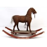 An Edwardian childs Pull along Horse mounted on a rocking base. Carved wooden frame with brown cloth