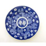 A small Chinese blue and white ceramic plate. Decorated with floral and foliate images. Indistinct