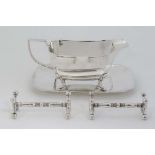 A silver plate sauce boat on squared stand together with a pair of silver plate knife rests