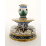 An Italian faience Ginori / Maiolica shaped candlestick, decorated with grotesque winged figures