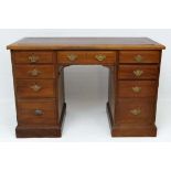 An Edwardian walnut kneehole / pedestal desk having on drawer flanked by 4 graduated drawer to