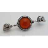 A white metal bar brooch with rams head detail to each end and set with a central carnelian