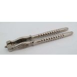 A pair of silver plated nut crackers with bobbin turned handles and patterned hinged ends . 6" long
