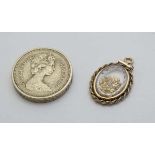 A gold and gilt metal pendant with glazed central section containing small gold nuggets . The