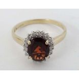 A 9ct gold ring set with central garnet bordered by diamonds  CONDITION: Please Note -  we do not