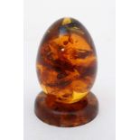 An amber ? model of an egg with inclusions on a circular stand 2 3/4" high  CONDITION: Please Note -