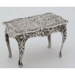 A .925 silver miniature dolls house table C-scroll and cherub decoration. Marked with import mark