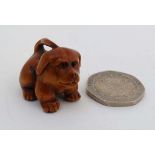 A hardwood netsuke formed as a puppy dog with glass eyes.  Signed. 1" high CONDITION: Please Note -