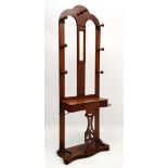 A late Victorian oak serpentine shaped hat coat and umbrella stand with central mirror, 7 hooks,