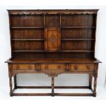 A 20thC long oak dresser in the 18thC style with 3 drawers, open plate rack and central cupboard