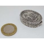 A .925 silver pill box of oval form with image to top depicting putto and swan and cast foliate