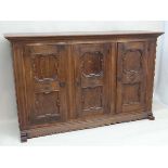 An early 20thC German oak 3 door cupboard with geometric like framed panelling, the doors opening to