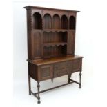 A c.1900 oak dresser with cupboards and open sections to top and 2 doors flanked by 2 cupboard doors