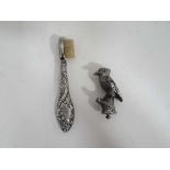 A small embossed silver handled tooth brush and white metal finial in the form or a bird (2)