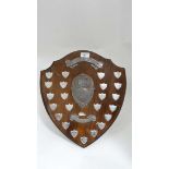 A c.1980 stained wood shield shaped trophy with 23 silver plate shields upon.  16 1/2" high