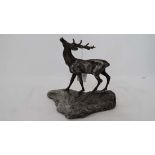 A silver plate model of stag with 10-point antlers mounted on a granite outcrop base.  the stag