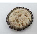 A late 19thC / early 20thC carved ivory brooch depicting Oriental figures in an interior with