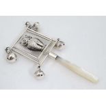 A white metal child's rattle decorated with owl and bells with mother of pearl teether handle.