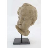 20thC Sculpture,
A reconstituted marble 2-dimensional head of a putto,
mounted on a stand. 
11 1/