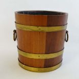A wooden ice bucket of coopered and staved form with brass banding and ring handles 9" high