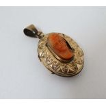 A late 19thC / early 20thC  gilt metal locket of oval form with carved coral cameo to centre 1" high