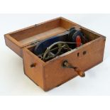 An early 20thC wooden cased electric shock machine with crank handle and hand held sections. The