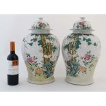 A large pair of 19thC Chinese famille rose vases with lids, decorated in polychrome with cranes amid