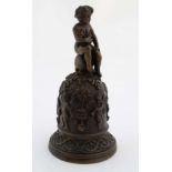 An old Italian bronze bell with handle formed as a putto sat upon a skull, the body decorated