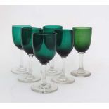 A matched set of green glass pedestal glasses, the green bowls on clear glass stems and circular