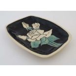 A rectangular Leaper Newlyn studio pottery dish, decorated with cream roses on a black ground and