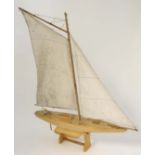 A mid 20thC single masted gaff-rigged pond yacht on wooden stand. Having articulated rudder, white