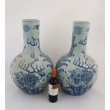 A large pair of blue and white Chinese vases decorated with Dogs of Foo in a stylised landscape with