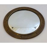 An early - mid 20thC convex mirror within an embossed porthole shaped brass frame 11 3/4"