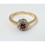An 18ct gold ring set with red stone to centre boarded by 7 platinum set diamonds CONDITION: