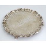 A silver salver / card tray on three scrolled feet and with engraved inscription ' Presented to