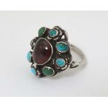 A white metal Austro - Hungarian style ring set with central garnet boarded by turquoise and