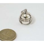 A pendant fob of stylised cricket ball form , the sphere opening to reveal locket like sections