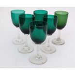 A matched set of green glass pedestal glasses, the green bowls on clear glass stems and circular