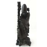 A large ebony carving of deity Fukurokuju with white metal inlay and stood holding a peach and staff