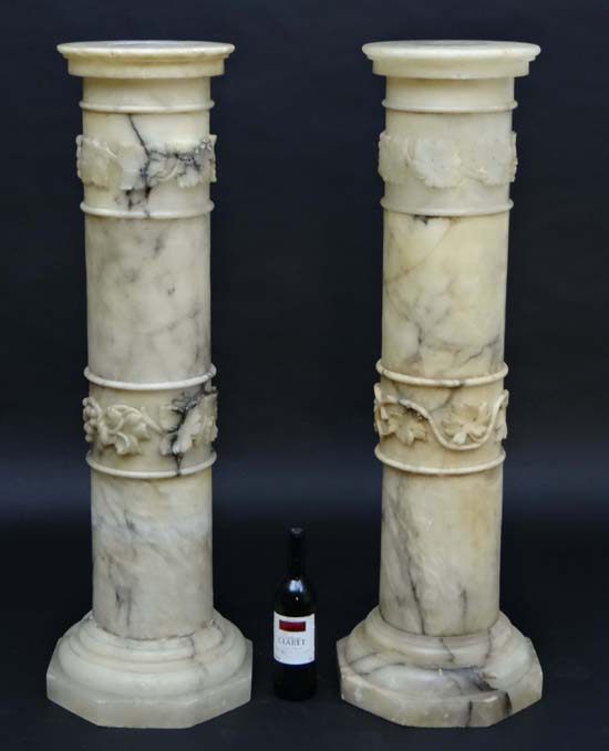 A pair of onyx / marble columns with octagonal bases, circular tops and bands of fruiting vine