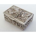 A silver plate pill box with fruiting vine, floral and wheat sheaf decoration 1 1/2" x 1/2" x 1"