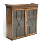 A 19thC mahogany astral glazed wall hanging cabinet with three shelves and blind fret carving to top