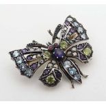 A gilt metal brooch formed as a butterfly set with various semi-precious stones including rubies,