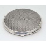 A late Art Deco silver powder compact with engine turned decoration and mirror inside lid.