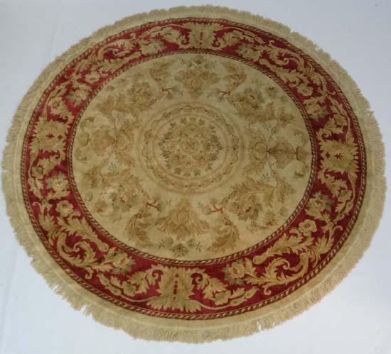 A late 20thC buff ground circular silk rug with rouge border. 84" diameter CONDITION: Please Note -